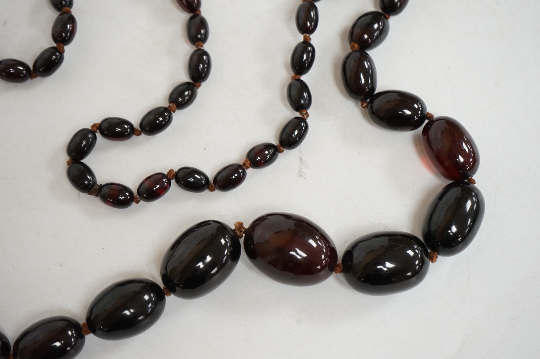 A single strand graduated simulated oval dark cherry amber bead necklace, 110cm, gross weight 90 grams.
